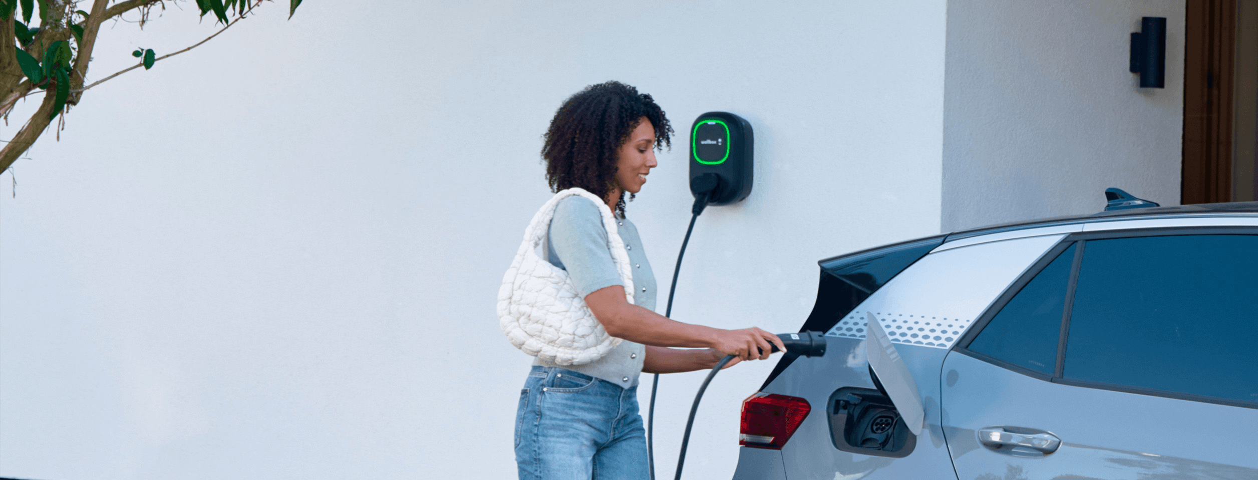 Driver connecting an electric car to a Wallbox home charger